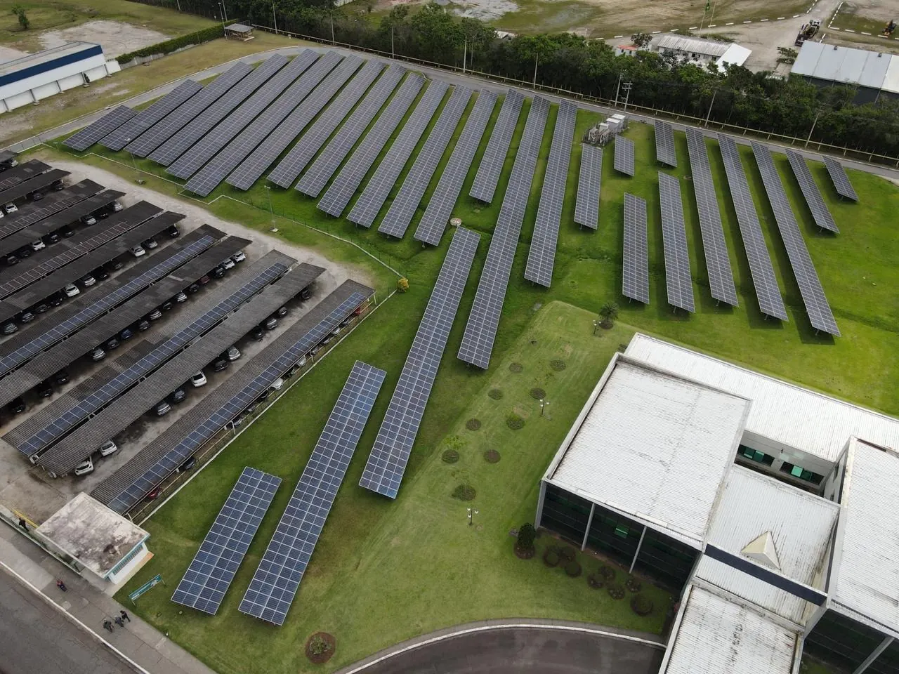 Vista aérea de usina solar em solo ao lado de um complexo industrial