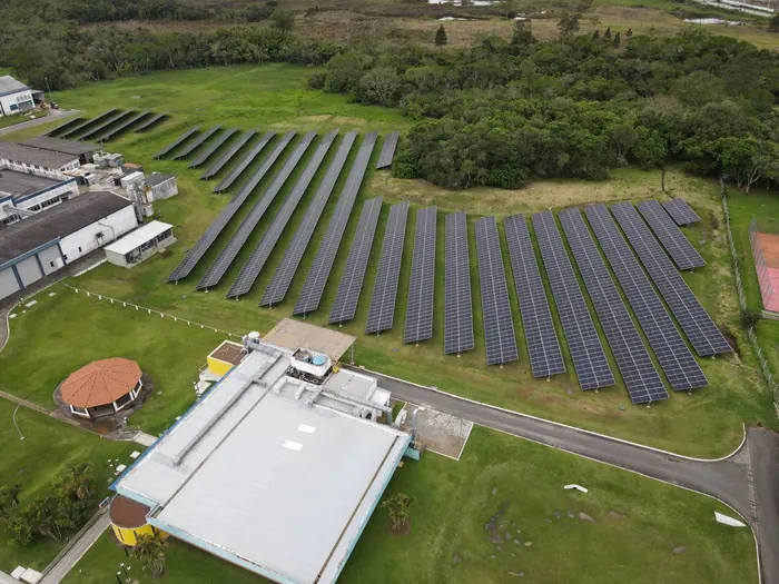 Vista aérea de usina solar em solo com fileiras de módulos